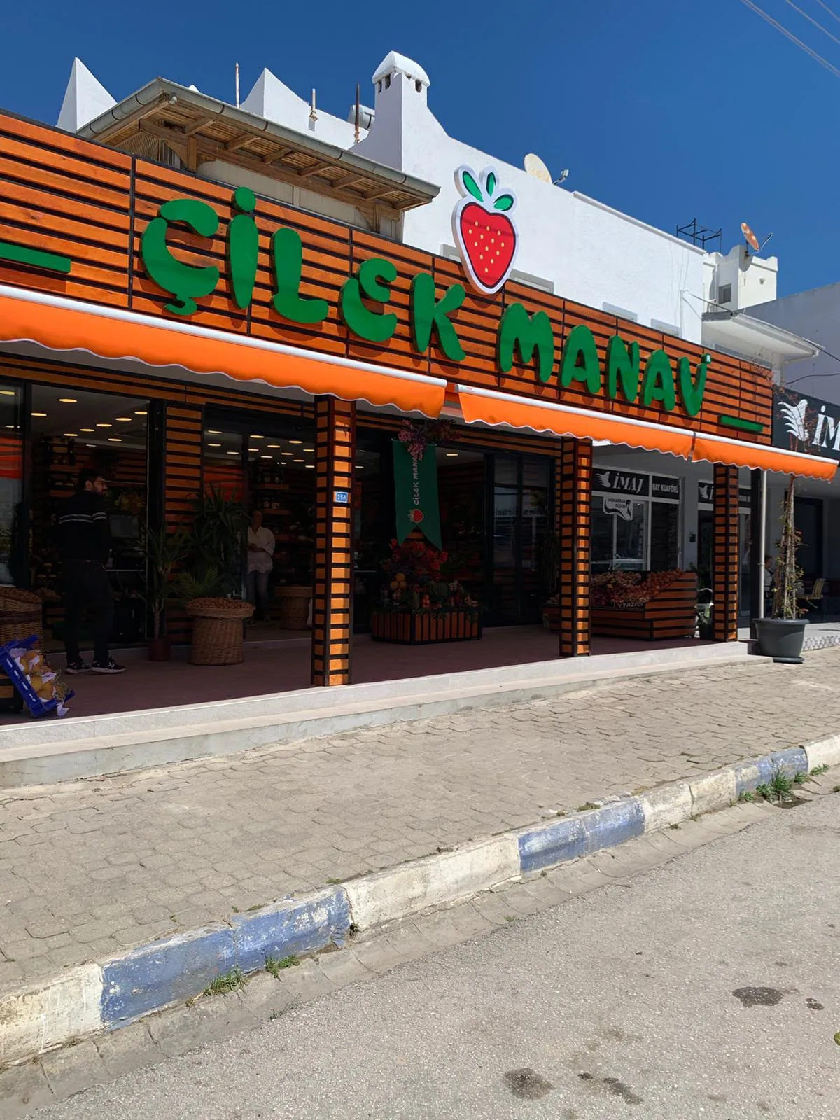 Yatay ahşap cephe kaplaması ve ışıklı tabelasıyla tamamlanmış manav mağazası